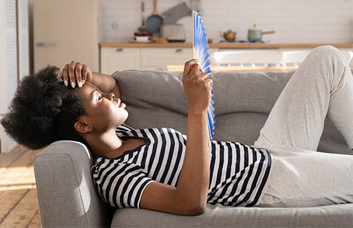 woman lying on sofa with fan