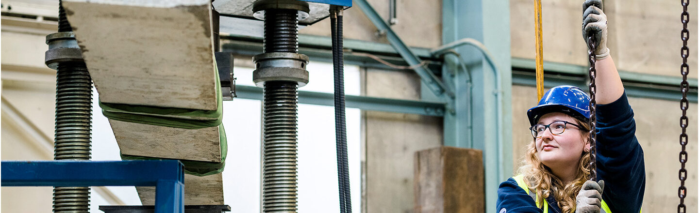 Technician pulling chain to raise concrete bar in testing lab at BRE