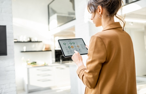 A woman checks a smart tablet that controls the indoor environment of her home.