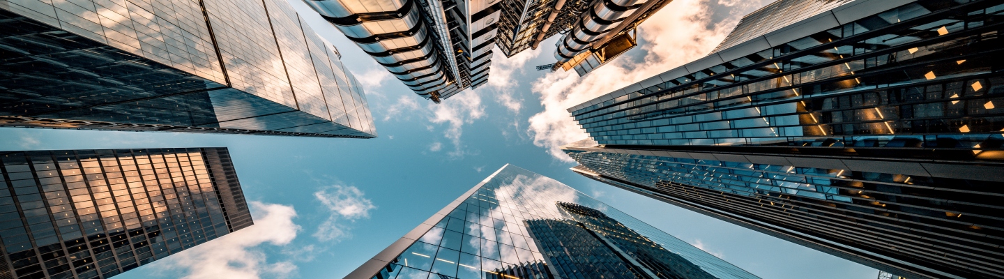 looking from the ground up, blue sky and skyscrapers reach upwards