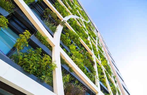 Looking up at a building has lots of plants and greenery incorporated into the facade.