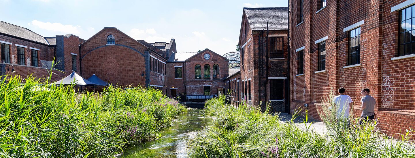 View of a river with brick mill buildings at Laverstock Mill